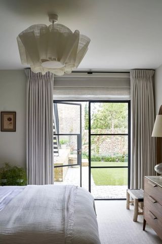 Neutral bedroom with Crittall doors onto garden