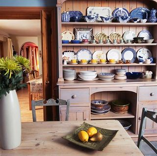 Kitchen dresser - Collection of blue crockery on lime-washed pine dresser in country kitchen with vase of flowers on scrubbed pine table