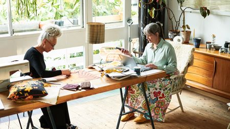 Two mature female roommates working at a table.