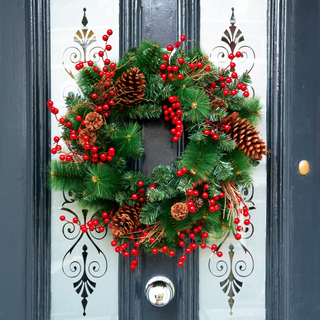 Grey front door with fake pine cone and red berry wreath