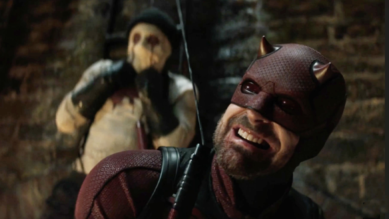 Dardevil (Cox) chokes Muse, who's strung up behind him.
