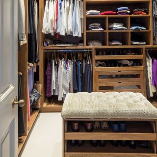 modern wooden wardrobe with clothes hanging on rail