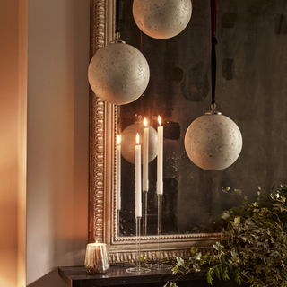 Hanging baubles and candles next to a mirror