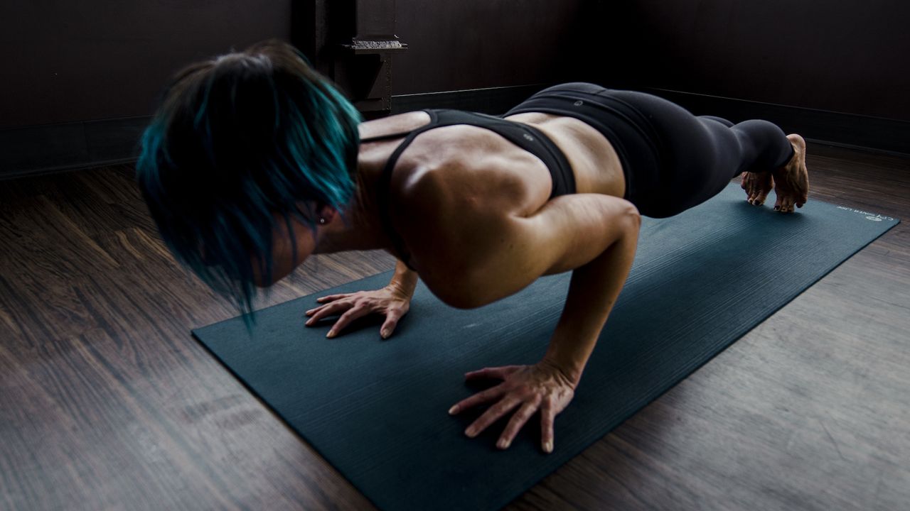 Strong woman doing push ups on a mat