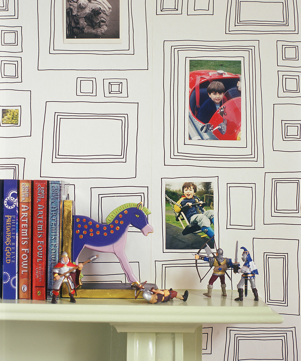 A close up of a gallery-style wallpaper personalized with photos and a mantelpiece with books and toys.