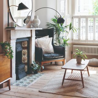 A living room with a retro-style wooden coffee table on a jute rug with a potted plant on top