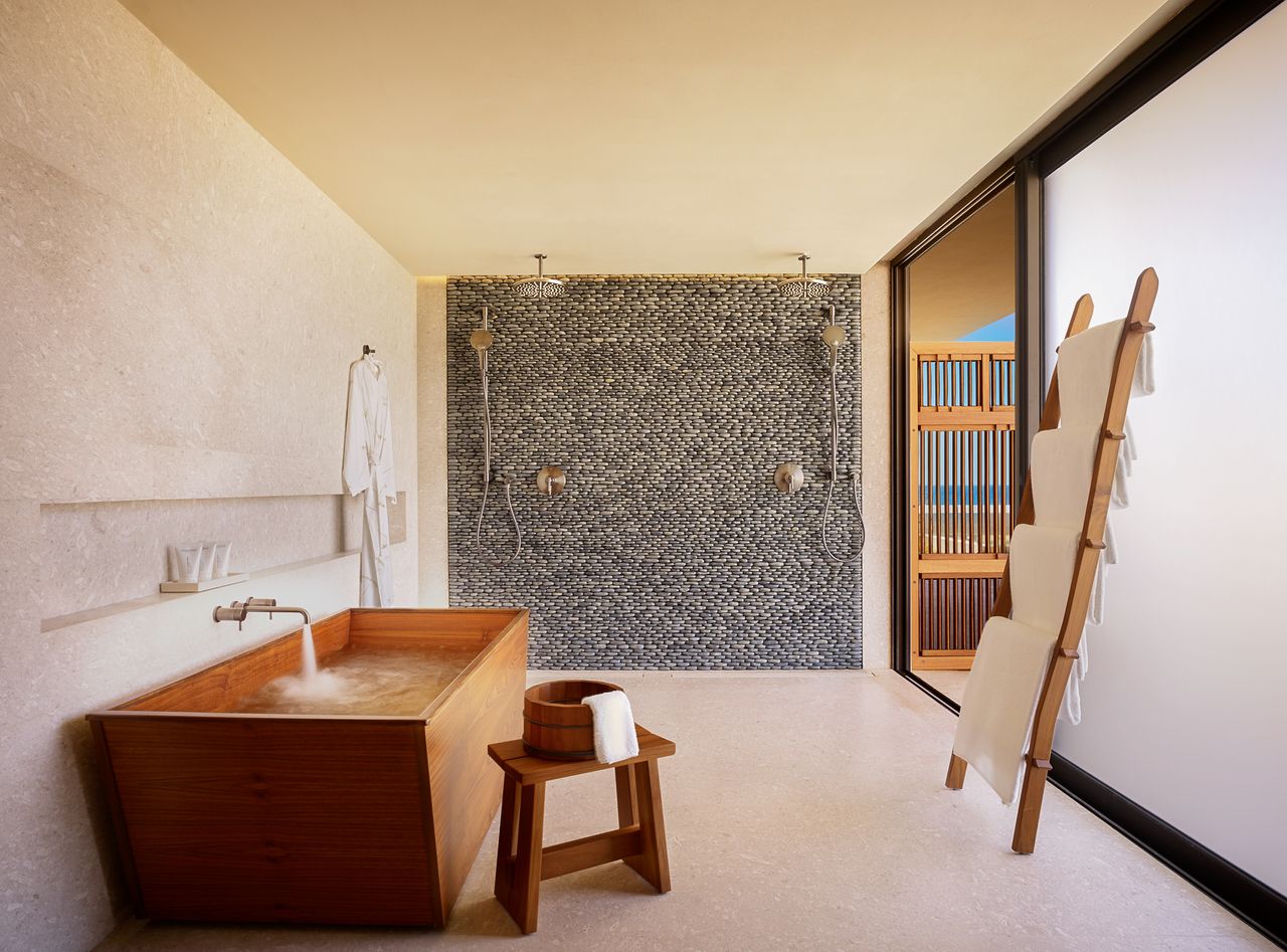 A bathroom with a large, wooden bathtub, and a curbless shower