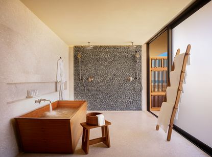 A bathroom with a large, wooden bathtub, and a curbless shower