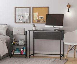 A gray desk with a desktop on it, against a wall.