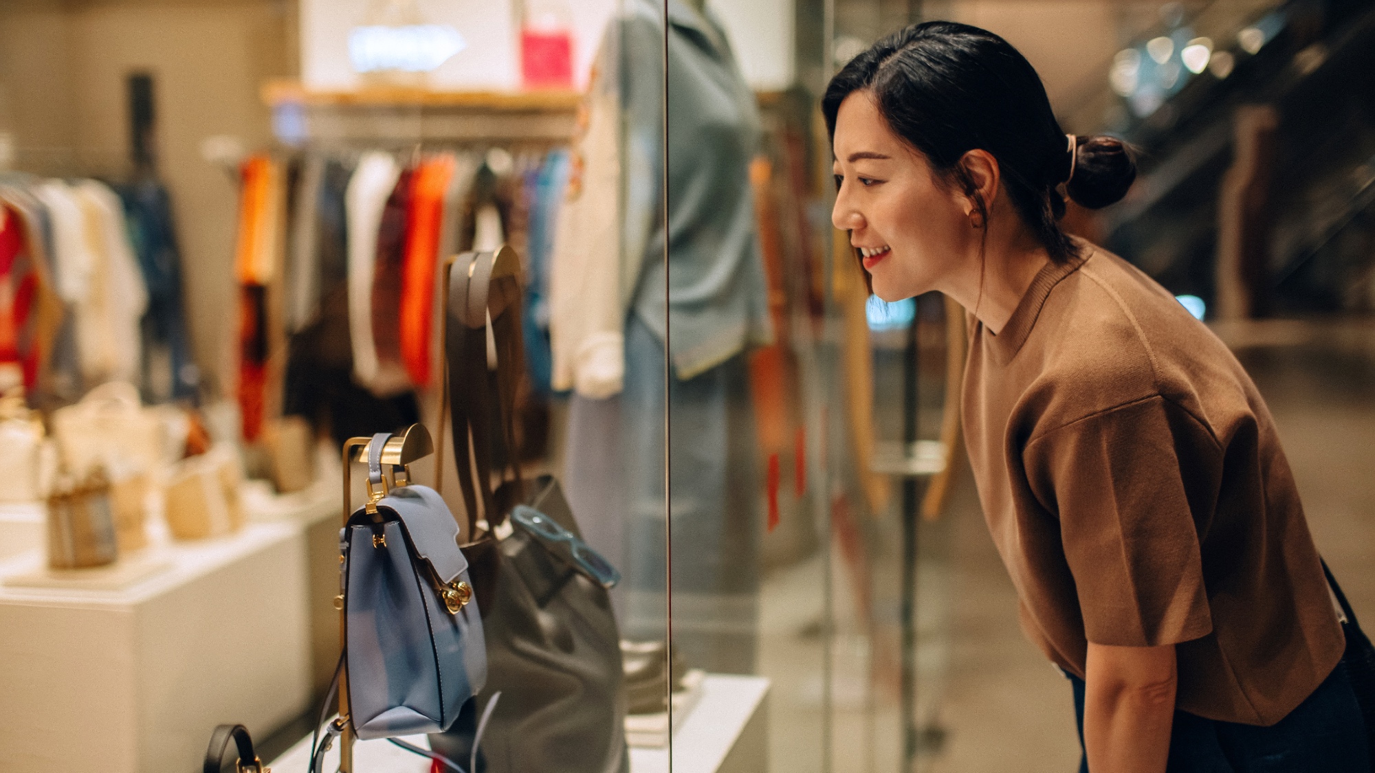 Smiling woman standing outside a store looking at window display in a shopping mall