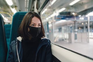 Woman on train wearing mask as people ask what stay local means
