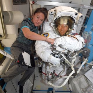 Jessica Meir (at left) and Christina Koch, seen here preparing for an earlier spacewalk by Koch, conducted the first all-female EVA on Friday, Oct. 18, 2019. Koch, as above, wore a spacesuit with the same portable life support system as used by Kathryn Sullivan, the first U.S. woman to walk in space on Oct. 11, 1984.