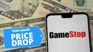GameStop logo shown on iPhone with U.S. dollars as background