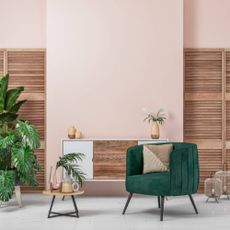 Green accent chair against a pink wall 