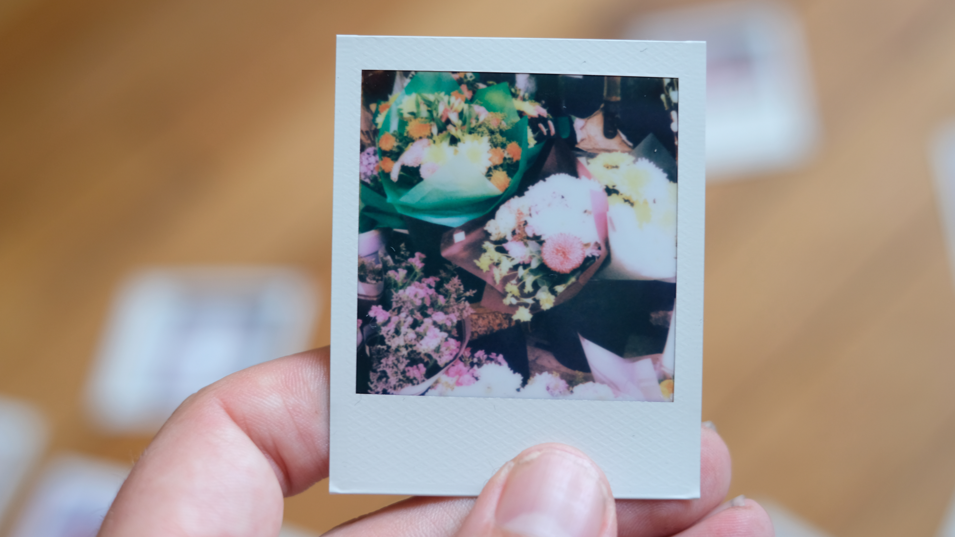 Photograph of prints made with Polaroid Go Gen 3 showing flowers outside of a shop