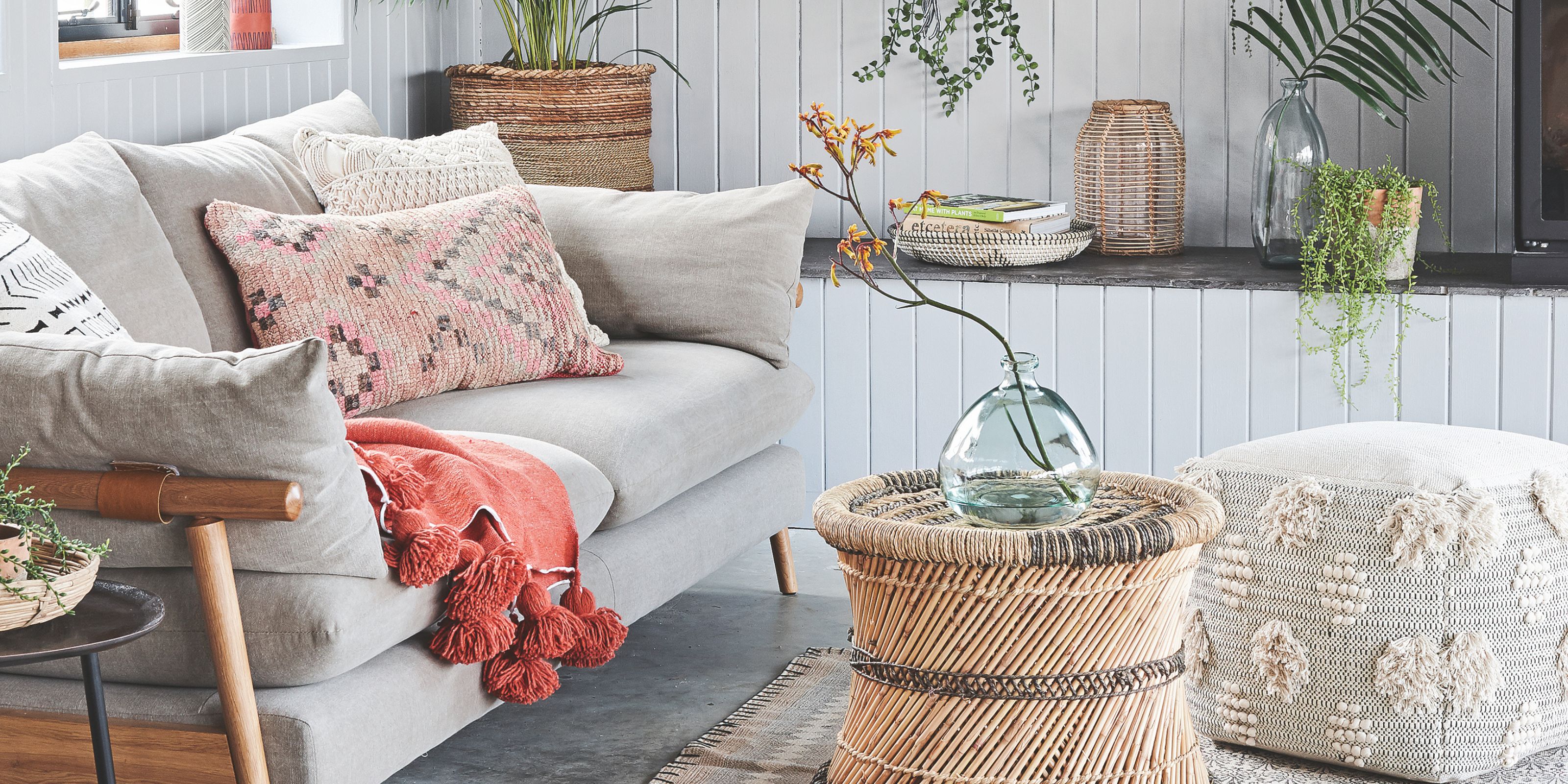 A grey sofa in a white conservatory with rattan footstall