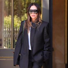 Victoria Beckham wears puddle pants with a matching blazer and white t-shirt in Paris.