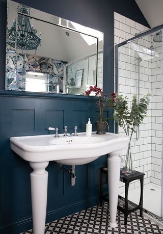 sink in a bathroom with a small mirror with wall paneling and metro tiles