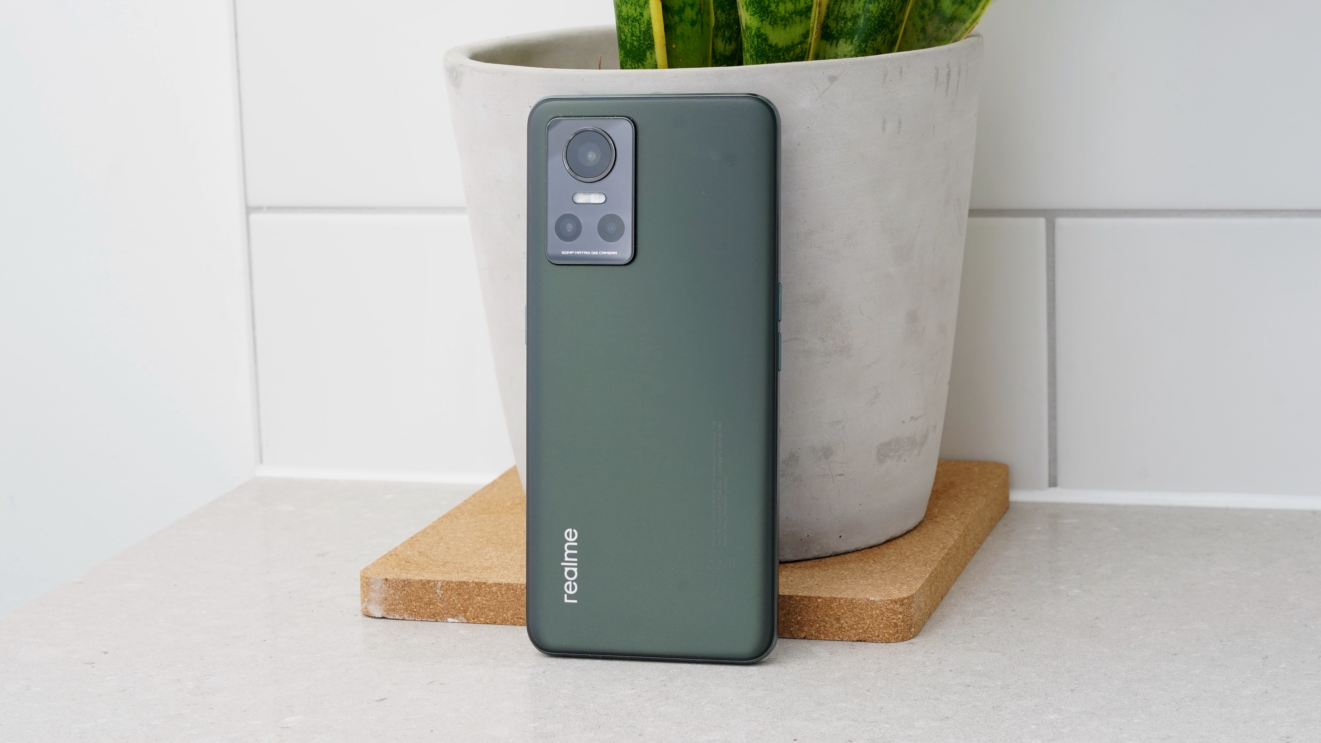 A Realme GT Neo 3 from the back, resting against a plant pot
