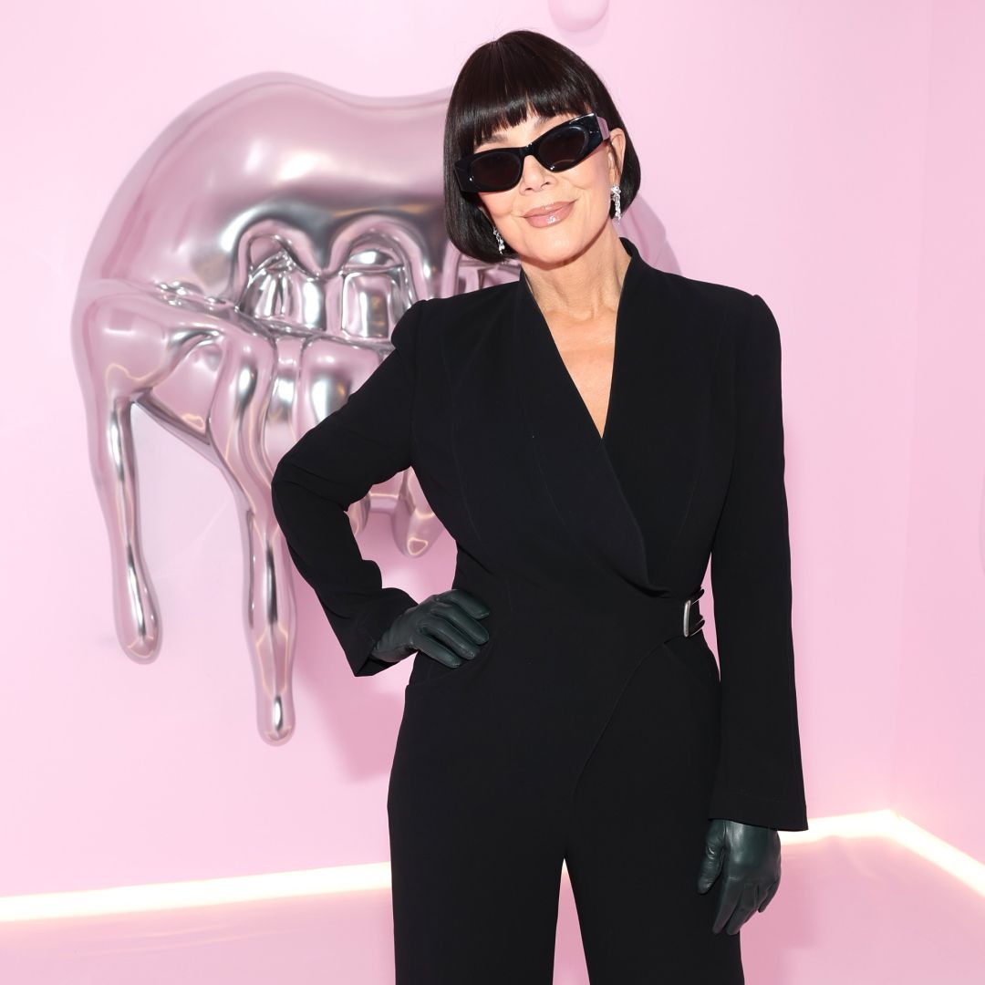 Kris Jenner wearing a black blazer and sunglasses. Her hair is styled into a short bob with bangs. 
