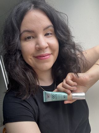 mica holding a tube of It Cosmetics Your Skin But Better CC+ Natural Matte with SPF 40