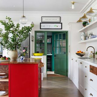 white kitchen with red kitchen island and green doors leading to back kitchen