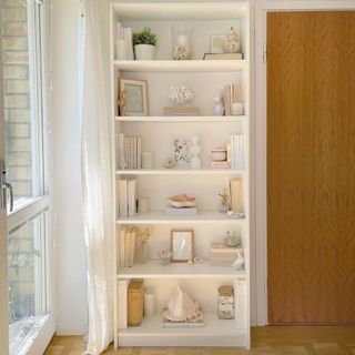 White open shelving filled with mixture of neutral ornaments with a natural feel to them
