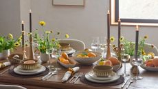 West Elm dining table with spring dinnerware and serveware including tapered candles and neutral tones