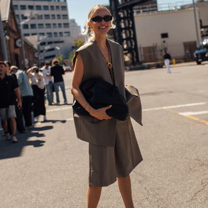 new york fashion week attendee wearing a beige suit set and sunglasses carrying a bag