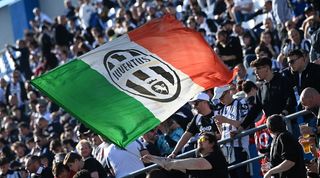 Juventus fans wave a huge Italy flag featuring their club colours during a match against Sassuolo in April 2023.