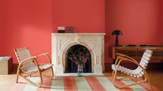 A red living room with a large marble fireplace and a red and white striped rug