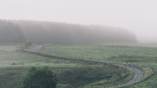 two commuters riding on a misty road