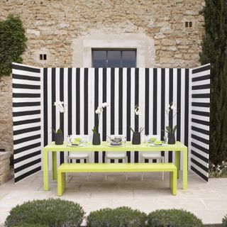 striped patio with yellow wooden table and bench