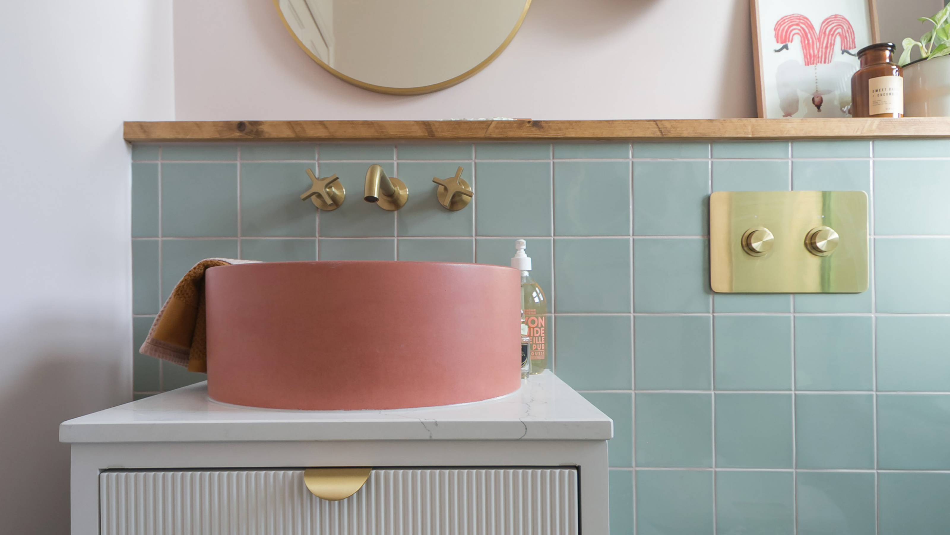a small bathroom with green wall tiles and a bright coral modern bowl basin