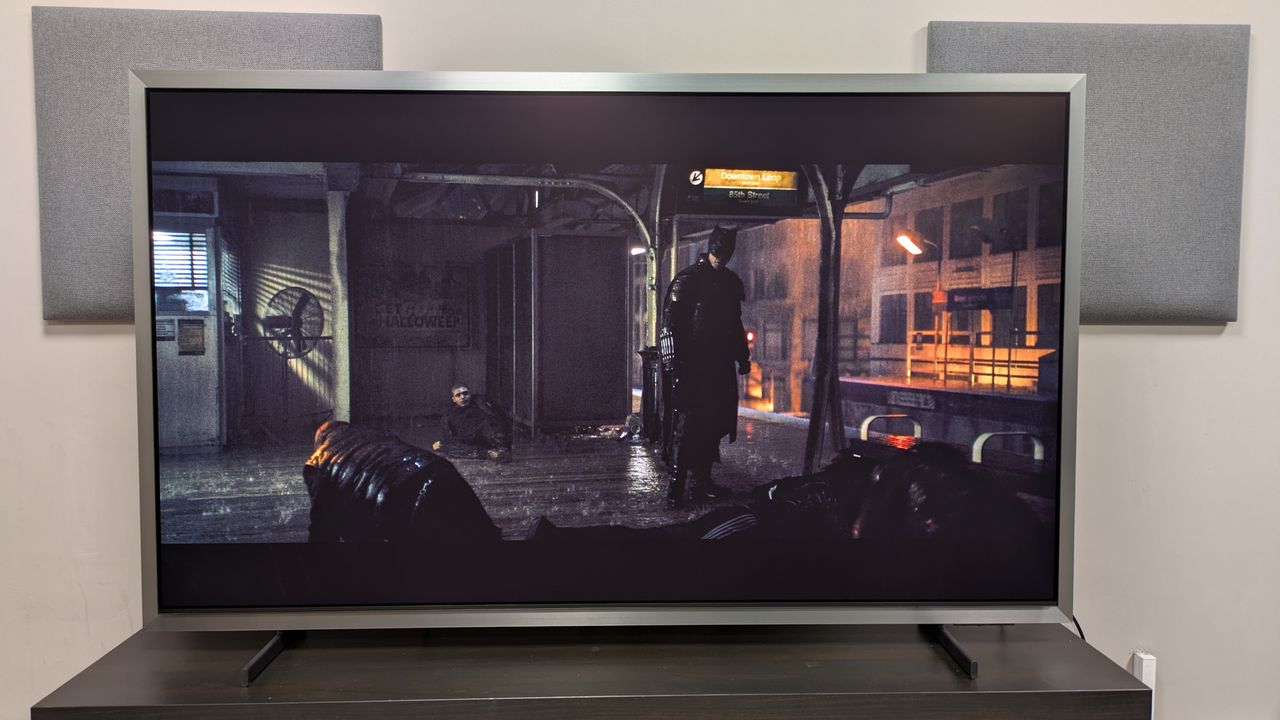 Samsung S95H with a shot of Batman stood on a subway platform from The Batman. The TV is set to Movie mode, and the picture is clear in very bright conditions