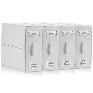 Four white labeled file boxes for storing linens