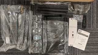 Bolts, parts and instructions for a tv bracket on grey carpet