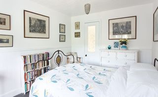 Guest room in a coastal home, with brass bedstead, vintage quilt and Hogarth prints