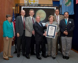 USPS and NASA officials join Guinness World Records adjudicator Jimmy Coggins (right) at the U.S. Postal Service's headquarters in Washington, D.C. on July 19, 2016. Also pictured, from left to right: Janet Klug, Citizens Stamp Advisory Committee chair; Glen Fountain, Johns Hopkins Applied Physics Laboratory; James Green, NASA Director of Planetary Science; Alan Stern, New Horizons principal investigator at the Southwest Research Institute; Megan Brennan, Postmaster General and USPS Chief Executive Officer and James Cochrane, USPS Chief Marketing and Sales Officer and Executive Vice President.