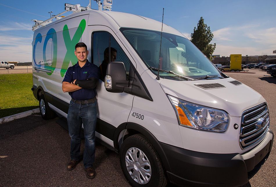 Cox technician in front of service truck 