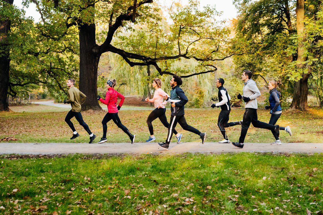 A group of men and women run through a green park