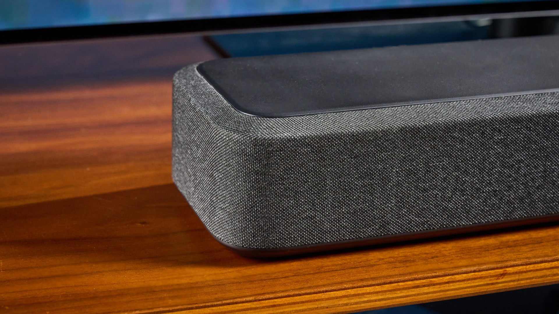 the denon home sound bar 550 with a gray mesh casing and touch controls for bluetooth on the top with a remote and smart home integration