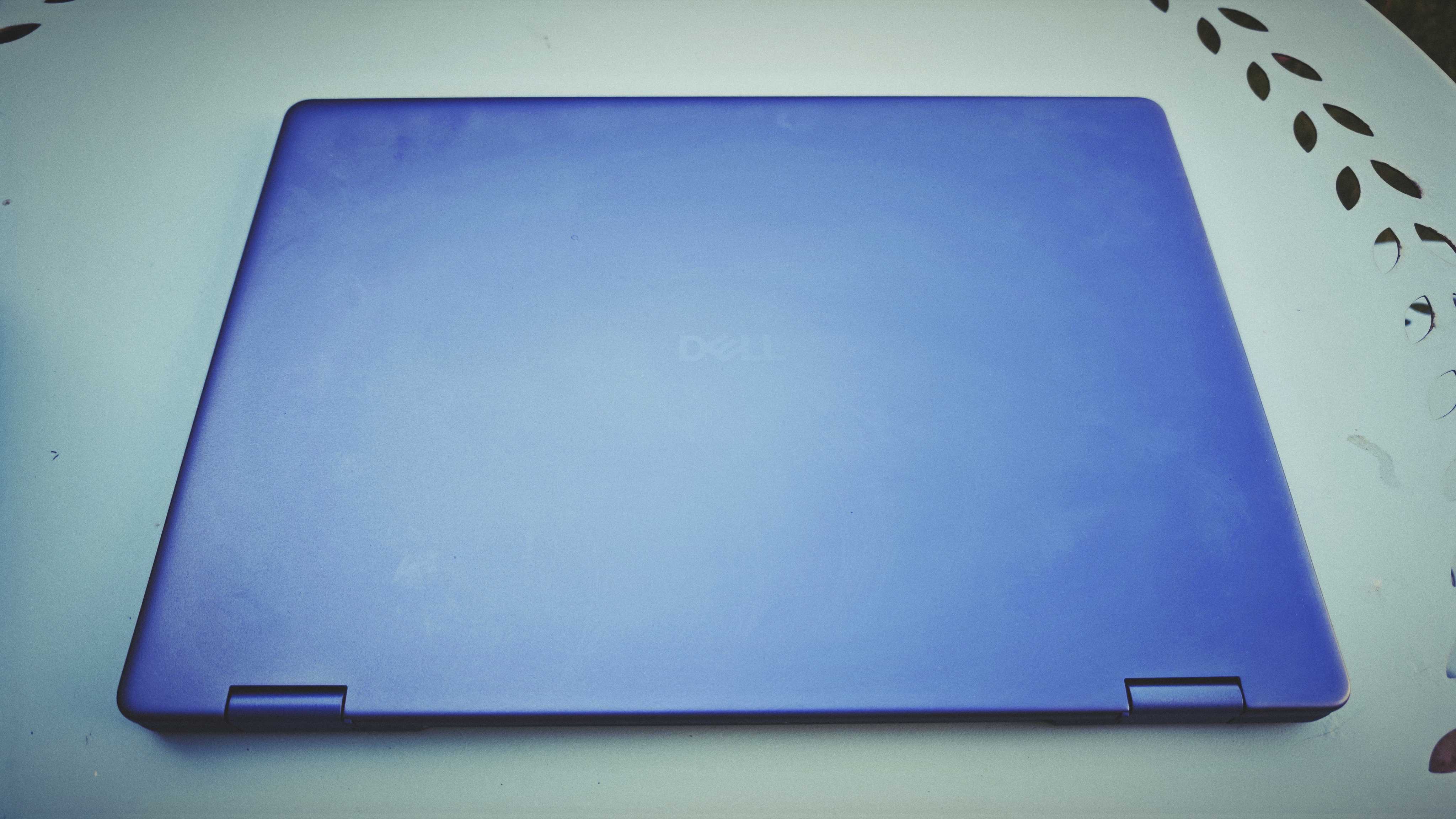 A Dell 16 Plus 2-in-1 laptop on a blue garden table