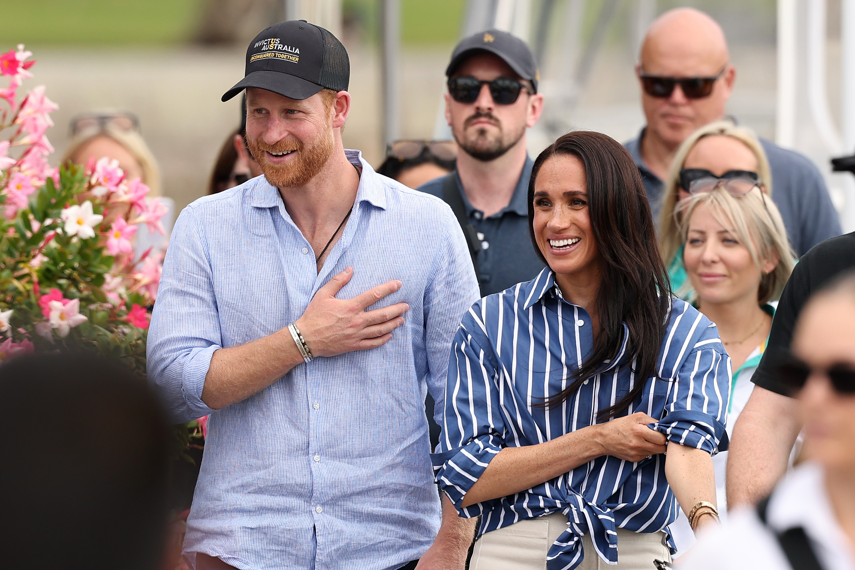 Prince Harry and Meghan Markle smiling and wearing blue shirts