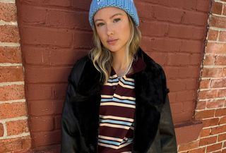 Woman in striped polo, hat, jeans, and coat