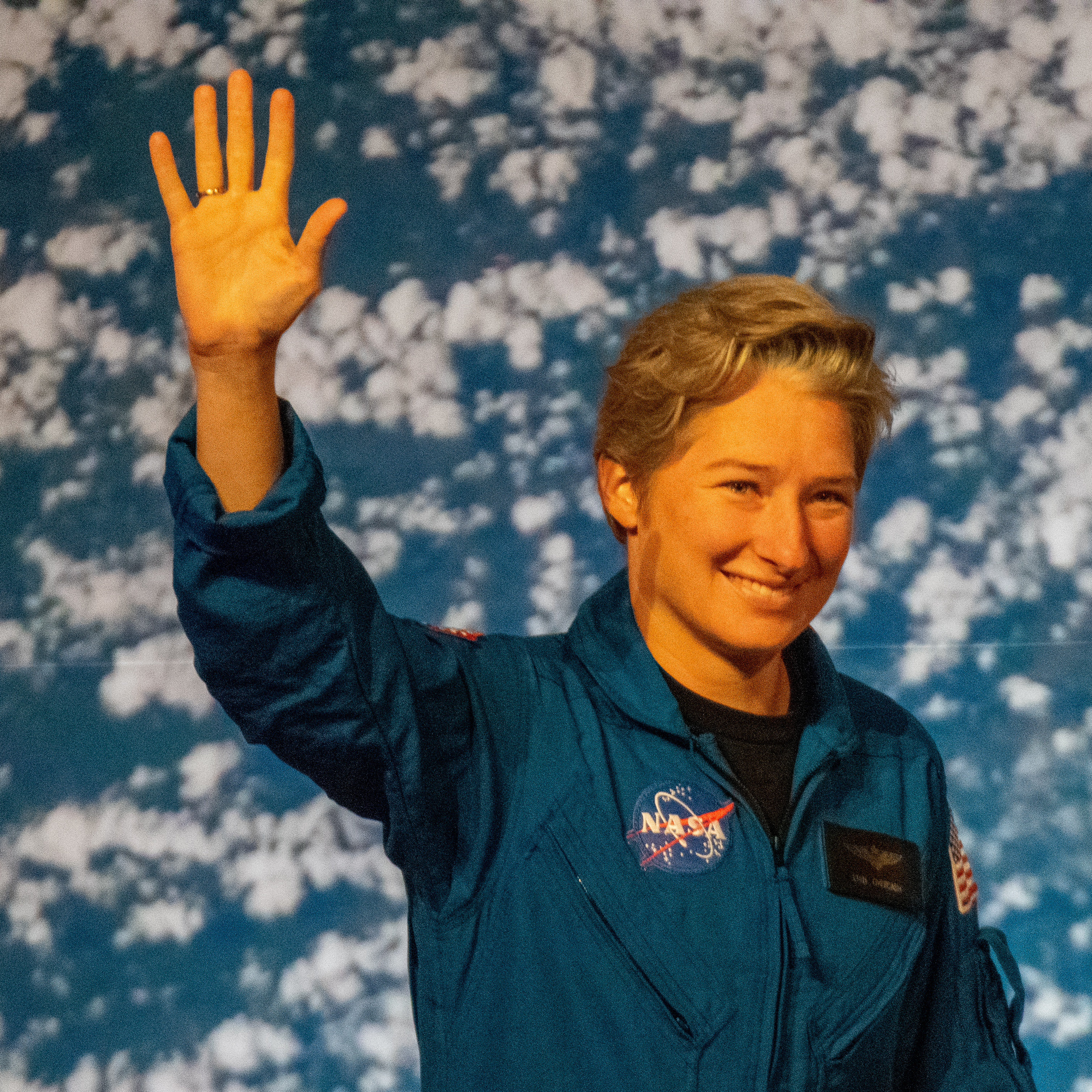 people in blue jumpsuits smile and wave.