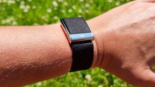 A close-up picture of our reviewer wearing the Whoop MG fitness tracker in the park