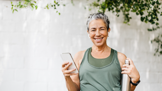 Woman smiling while listening to phone and holding water