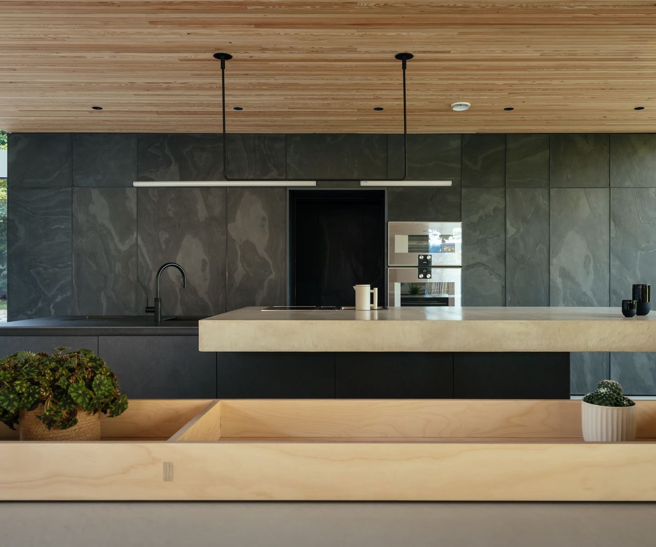A grey kitchen with a porcelain island and wooden ceiling