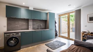 utility room with green units and dog bed
